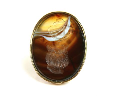 A 9ct yellow gold signet ring, set with a large ornage, brown, and white hardstone carved with a monogram and a terrier's hea