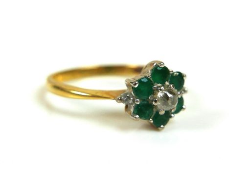 An 18ct yellow gold flowerhead ring, set centrally with an old cut diamond, 3.5mm, surrounded by six emerald petals, each 3.0