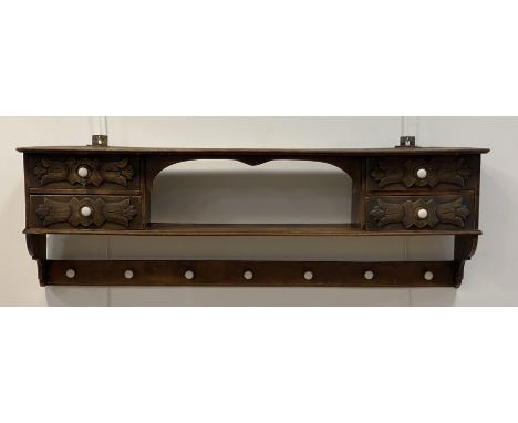 A late 19th/early 20th century oak hall rack, fitted with an open shelf and four acanthus carved drawers above seven ceramic 