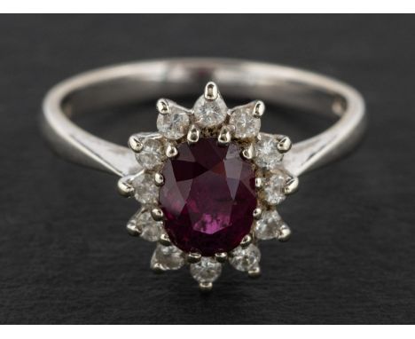 An 18ct gold, oval, mixed-cut ruby and round, brilliant-cut diamond cluster ring, estimated ruby weight ca. 1.55ct, total est