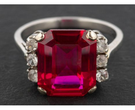 An Art Deco style, octagonal, step-cut, synthetic ruby dress ring, each side of the synthetic ruby flanked by three white sap