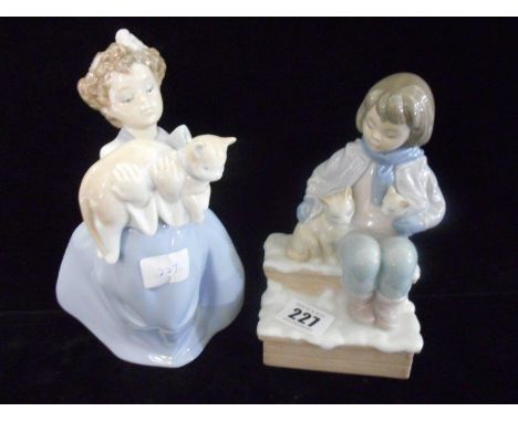 Two Lladro figures of a girl in long dress holding a cat and a boy seated on a bench with two cats, both boxed