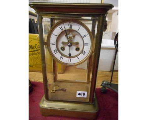 A four glass mantel clock with white enamel dial, visible escapement, in a bevelled glass and brass case