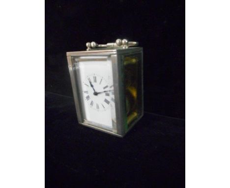 A small carriage clock with white enamel dial, in a silver plated case with glass sides
