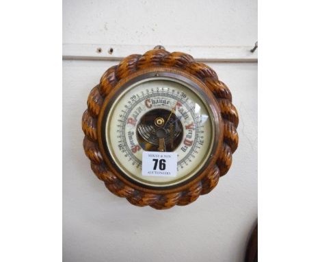 An aneroid barometer on an oak mount with rope carved edge and a brass candlestick
