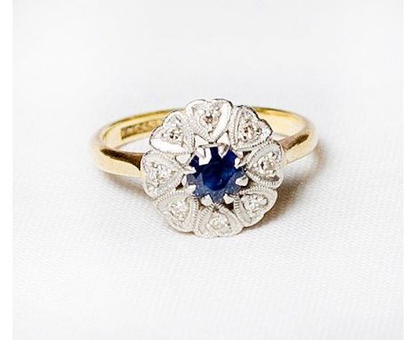 A lady's cluster ring set sapphire surrounded by diamonds, on an 18ct. gold and platinum shank