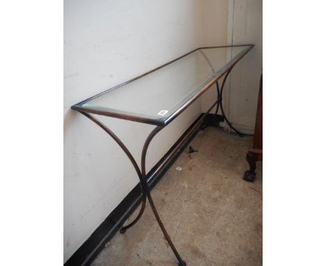 A modern brushed steel console table with bevelled glass top