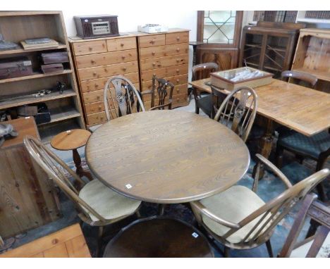 An Ercol elm dining table on turned centre column and downswept legs and four Ercol chairs with spindle backs, pierced centre