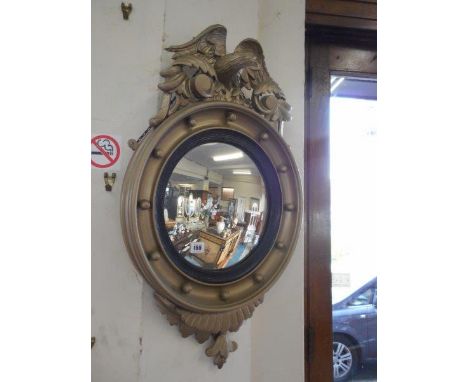 A convex wall mirror in a gold painted frame with eagle surmount and ball decoration, a barometer and thermometer on an oak m