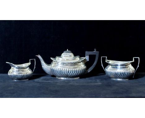 A silver three piece tea service with half fluted decoration - Sheffield 1927 - 34 3/4oz. gross
