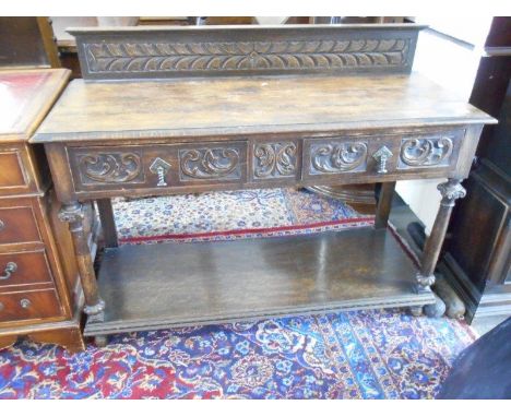 An oak buffet with low raised back, carved decoration, fitted two frieze drawers, turned supports, the base fitted shelf unde