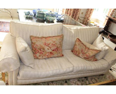 A white upholstered three seater sofa. 