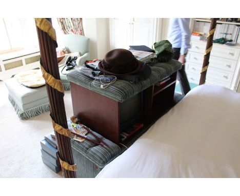 A GREEN UPHOLSTERED OTTOMAN, with button top and tasselled trim, opening to reveal a TV.

