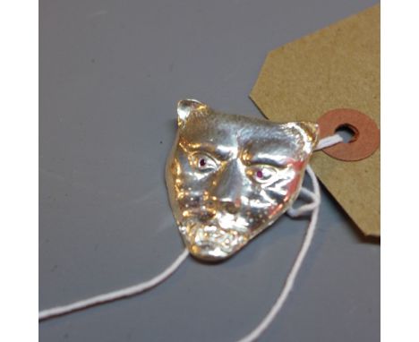 A silver leopard head pendant with ruby eyes