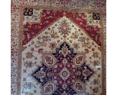 A Heriz style carpet with central medallion on a beige field contained by many borders. 280cm x 200cm