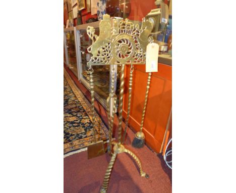 A set of Georgian brass fireside tools on a matching brass stand, the stand decorated with a pierced and engraved heraldic cr