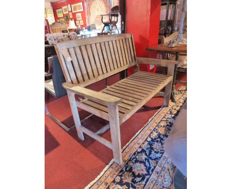 A weathered teak two seater garden bench. H-93cm W-120cm D-58cm