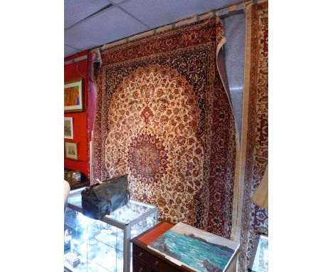 A Keshan style carpet with central floral medallion surrounded by vines on a beige field and contained by borders. 280cm x 20