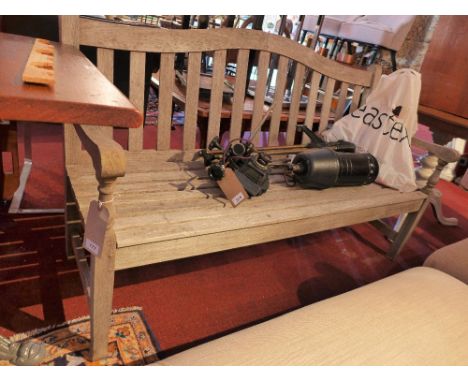 A weathered teak three seater garden bench with arched back. H-84cm W-146cm D-57cm