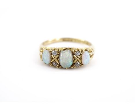 An early 20th Century opal and diamond ring, set with a central oval opal cabochon of approx .25 ct, set between smaller opal