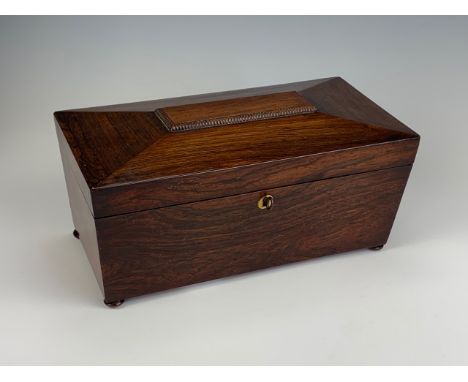 A late Georgian rosewood sarcophagus-form tea caddy, containing a pair of wooden tea canisters and a ceramic bowl, 33 cm x 17