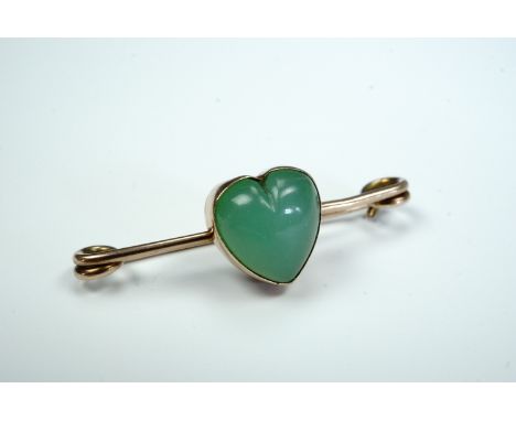 An early 20th Century jade brooch, comprising a collet-set heart-shaped cabochon set in a yellow metal pin, (marked 9 ct and 