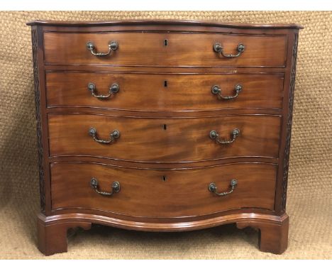 A George III serpentine fronted mahogany commode, having a plumb pudding top, the canted leading edges decorated with blind f