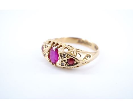 An early 20th Century ruby and diamond ring, the oval face sunken-set with a central oval ruby of approx 0.6 ct between a pai