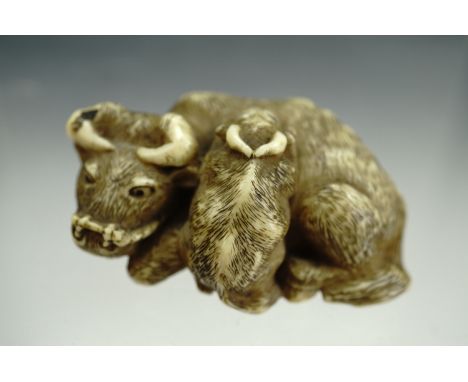 A Meiji Japanese carved ivory netsuke modelled as a water buffalo and calf, 4 cm