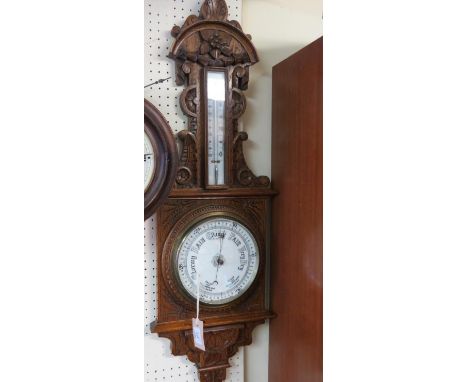 A Victorian carved oak wheel barometer, with printed thermometer and barometer dials, 38in. 