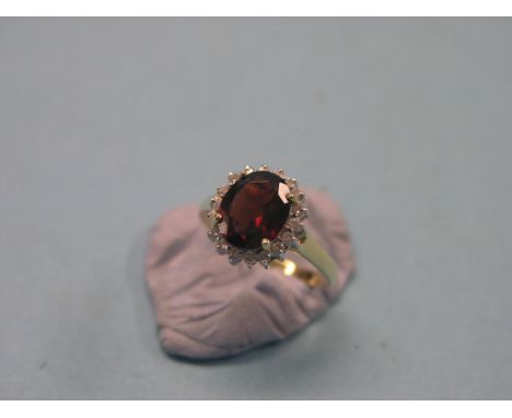 A modern 9ct. gold cluster ring, large central garnet surrounded by claw-set diamond chips, size M