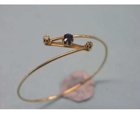 A Victorian yellow metal bangle, claw-set single sapphire and two small diamonds, in hinged cross-over setting, initialled CC