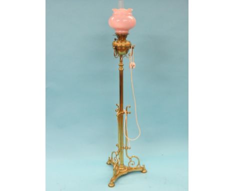 A Victorian telescopic brass floor lamp, on tri-form scroll base, fluted brass reservoir and opaque glass shade, converted to