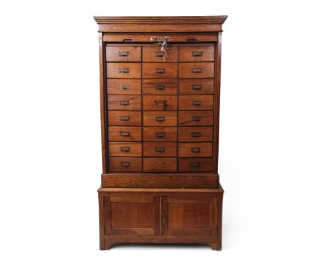 Early 20th century oak office cabinet with tambour shutter front enclosing a fitted interior of 24 drawers on a plinth base w
