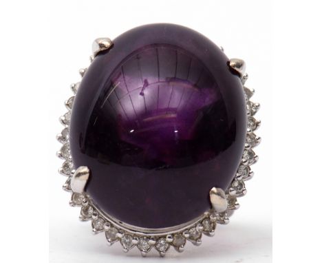 Large amethyst and diamond dress ring, the large oval shaped cabochon 24mm x 24mm, four claw set and raised within a small di