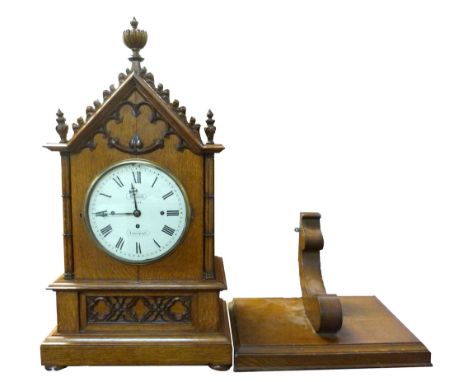Large oak cathedral style bracket clock with matching bracket, arched top with central decorative finial, circular face with 