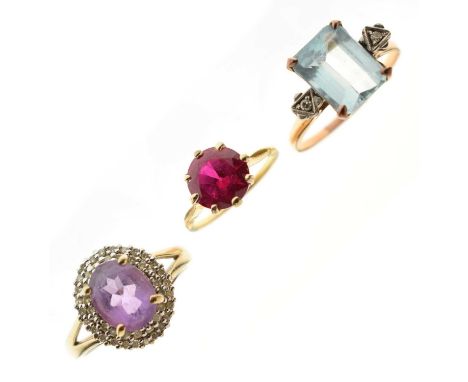 Three unmarked yellow metal dress rings comprising a synthetic ruby ring, a blue stone and diamond ring, and an amethyst and 