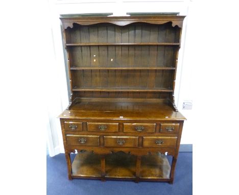 AN OAK DRESSER, the plate rack above an arrangement of seven various sized drawers, concave squared front supports and lower 