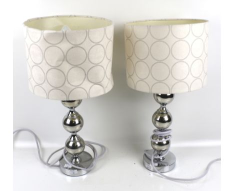 A pair of contemporary chrome bobbin like table lamps. The fabric shades printed with circles, H48cm