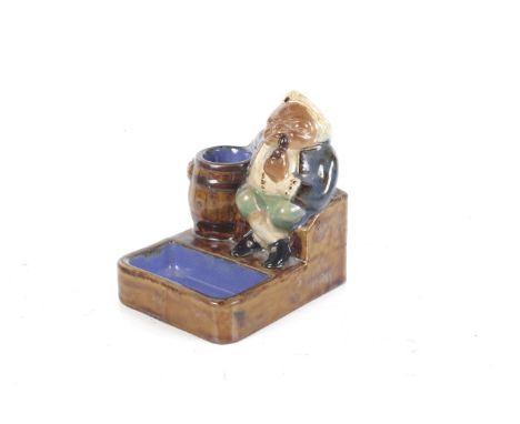 A Royal Doulton Lambeth novelty pipe rest. Modelled as a man smoking with an arm around a barrel, H9cm Condition Report: Over