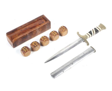 A 20th century dagger and a boxed set of dice. The dagger with a brass handle inlaid with ebony and bone, with a sheath, L22c