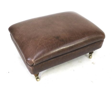 A modern oblong leather pouffe. with turned wooden supports, on brass  casters, H35cm x W69cm x D50cm