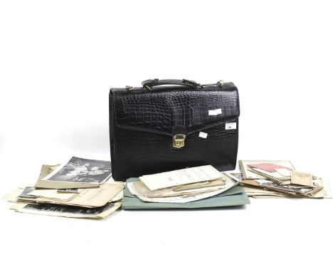 A black briefcase containing an assortment of ephemera. The briefcase with a handle to the top and gilt buckles, L41cm, the e