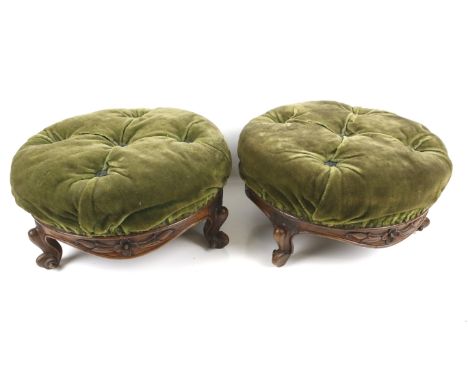 A pair of Victorian footstools. The carved mahogany frame with three cabriole supports, upholstered in green button back velv