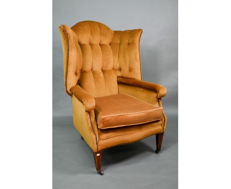 An antique button and wing backed armchair raised on square tapering front legs to ceramic casters, later gold upholstered 