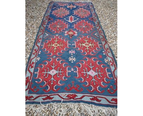 A vintage Turkish Kilim, red 'hooked' medallions on blue field, 300 x 123 cm 