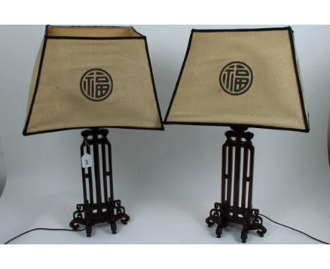 Pair Chinese carved hardwood table lamps of traditional form, with Chinese-style shades, on scroll feet, 65cm high