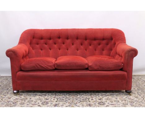 Late 19th / early 20th century red button back upholstered settee, raised on bun feet and castors