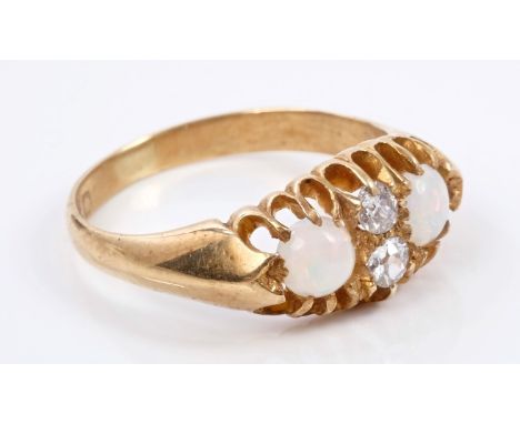 Late Victorian opal and diamond ring with two round cabochon opals, interspaced by two old cut diamonds in carved gold claw s