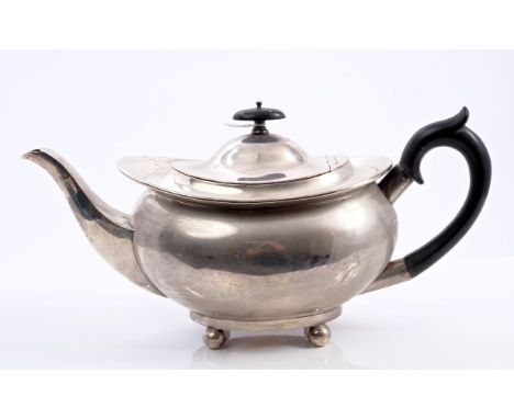1920s silver teapot of bellied form, with flared rim, ebony scroll handle and hinged domed cover with ebony finial on four ba
